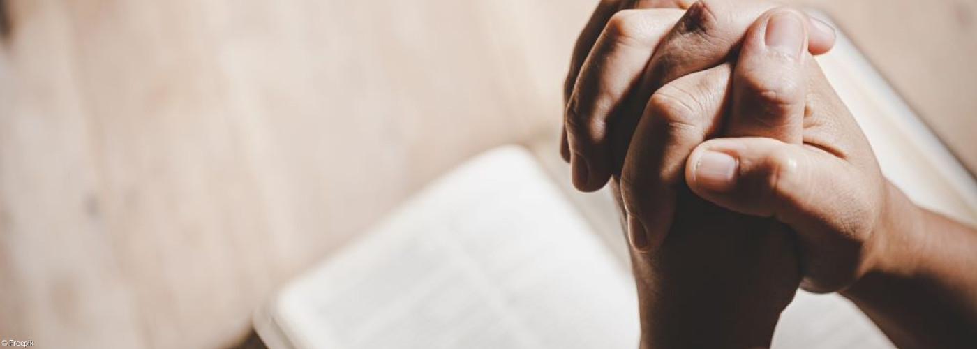 Betende Hände über einem Buch